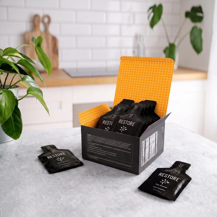 Open box of ROOT Brands Restore 15 mL sachets on a kitchen counter.